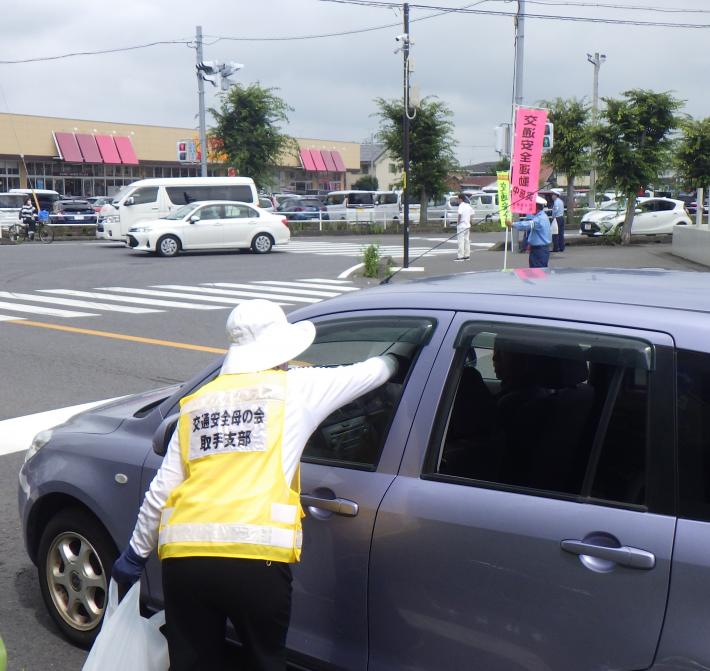 交通安全母の会員が運転手に啓発品を配布しする様子