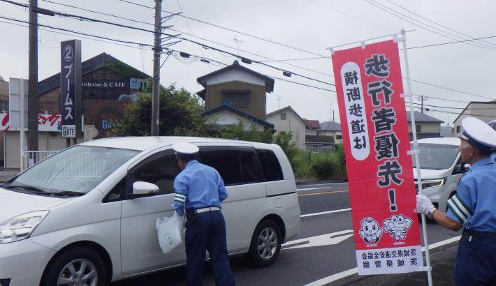 交通安全推進指導隊員が運転手に啓発品を配布する様子