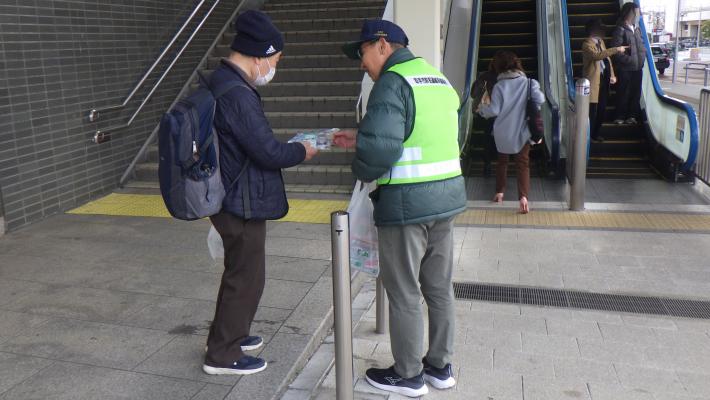 啓発品を市民に配布する防犯連絡員の男性