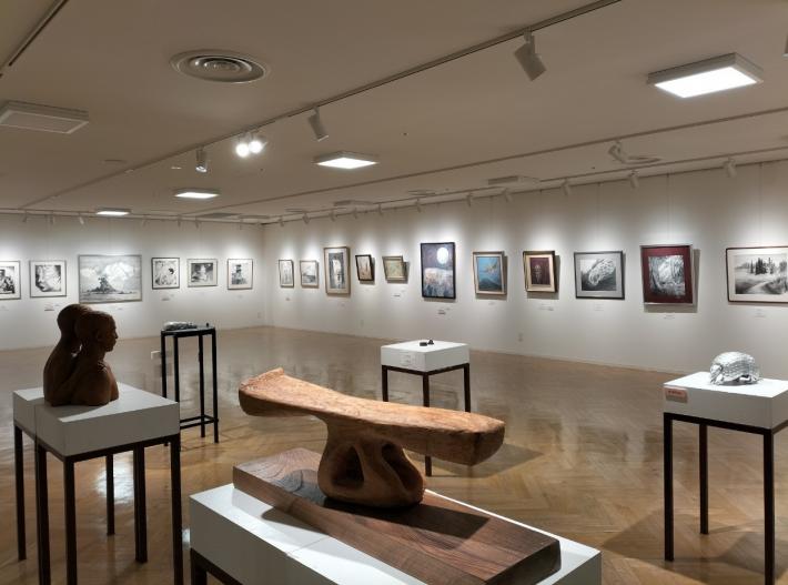 令和6年度取手市民美術展1部会場風景。手前に彫刻が数点飾られており、奥の壁には日本画が数多く飾られている。