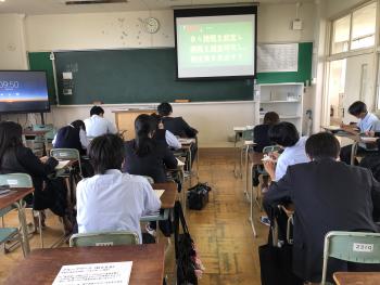 制服を着た学生が机に座って書き物をしている