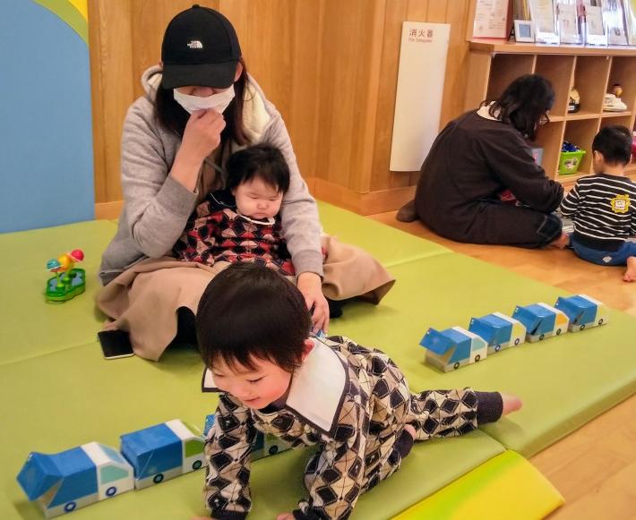 男の子が新聞紙をゴミ回収車に入れる写真