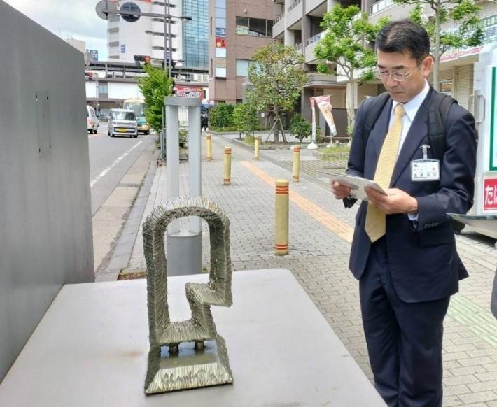 道路沿いに置かれた芸術作品を鑑賞する大人