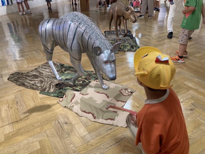 かがんで動物の作品を見る子ども