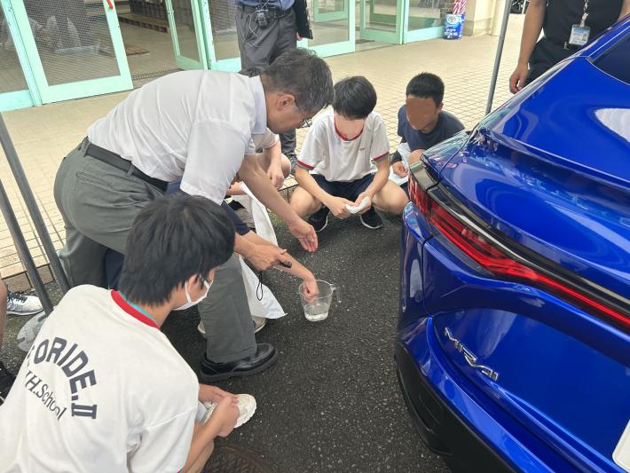 ビーカーに入った水をさわるこどもたち