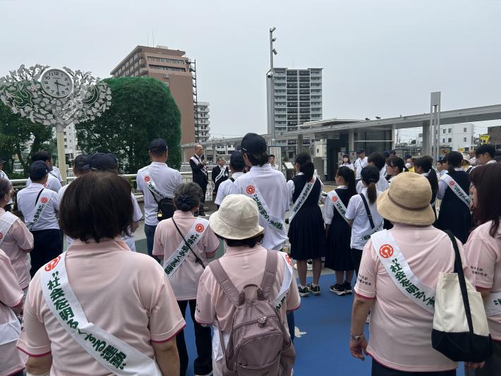 駅前に集まった参加者に向けて話をする男性