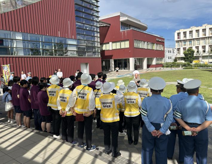 ステージ前に集まった直立の参加者の前であいさつをする男性