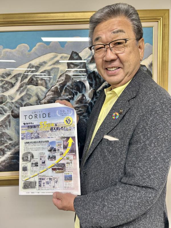 市制施行55周年を記念した広報紙を手にもつ男性