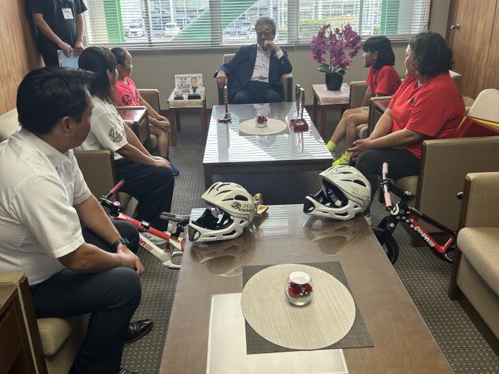 部屋に置かれたランバイクと座って話をする小学生と男性