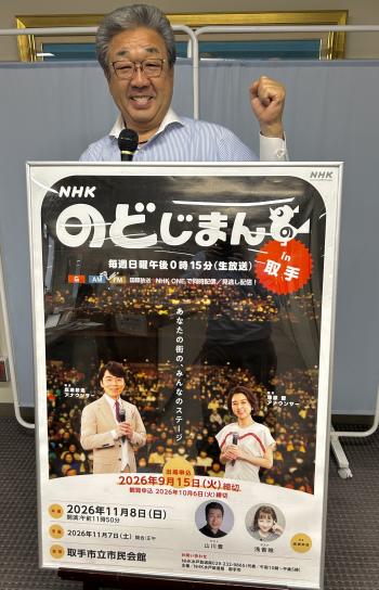 のど自慢のポスターの裏に立ちマイクを持つ男性