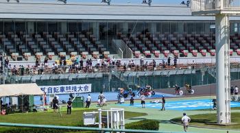 自転車競技大会と書かれた看板の前を走る自転車が複数台ある