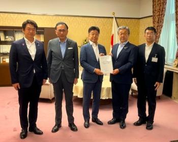 要望書を持つ2名を中心に、スーツを着て立つ男性5名