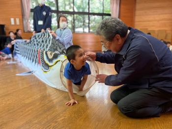 鯉のぼりをくぐる男の子と見守る男性