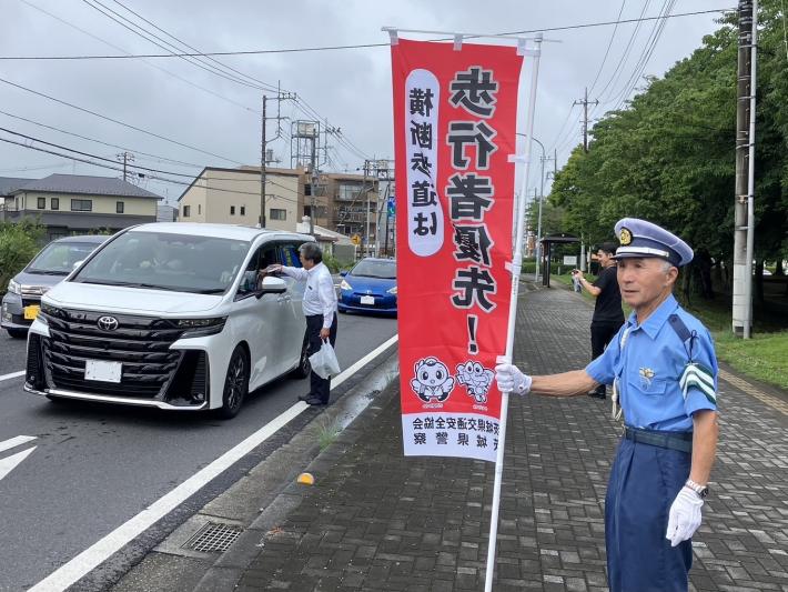 車の窓から啓発グッズを手渡す男性