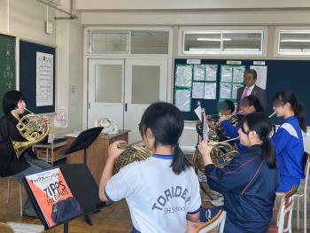 金管楽器を座って吹く大人と学生