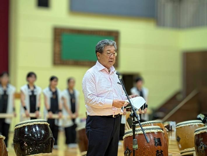 和太鼓に囲まれた場所であいさつをする男性