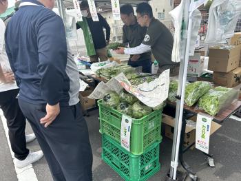 テントの下に並べられた野菜を販売する様子