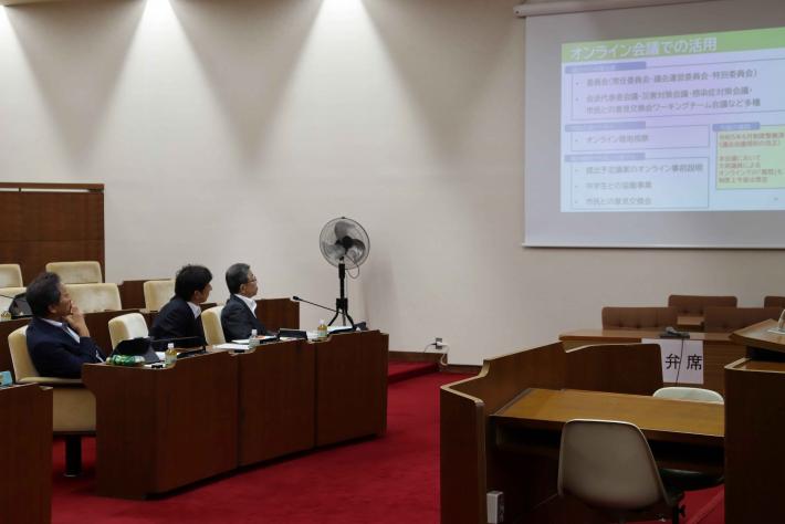 愛知県田原市議会の議員らがスクリーンに投影された資料を見ながら説明を受けている様子