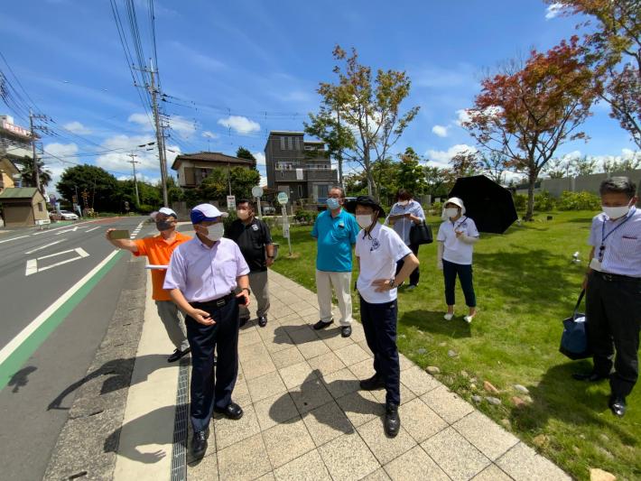 芝生とコンクリートでできた歩道に男性6名と女性2名が立っている