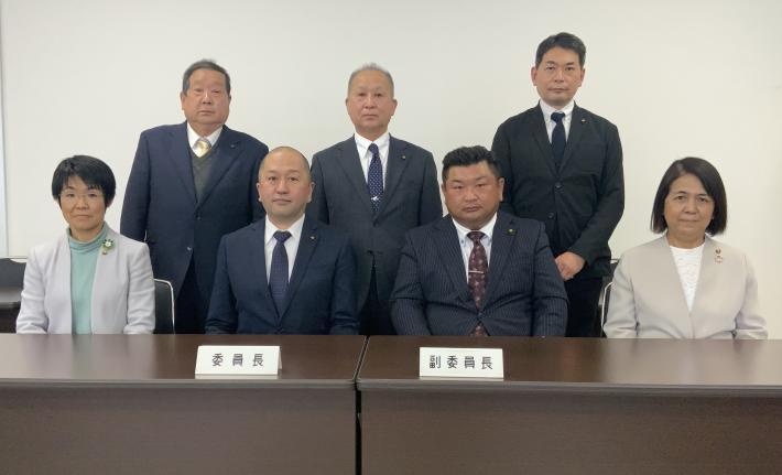 総務文教常任委員が机を前に、前列4人が座り、後列3人が立っている