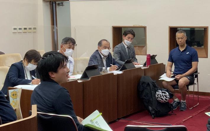 取手市議会の議場の座席に議員4人が座って、向かい合って座っている市民と話をしている