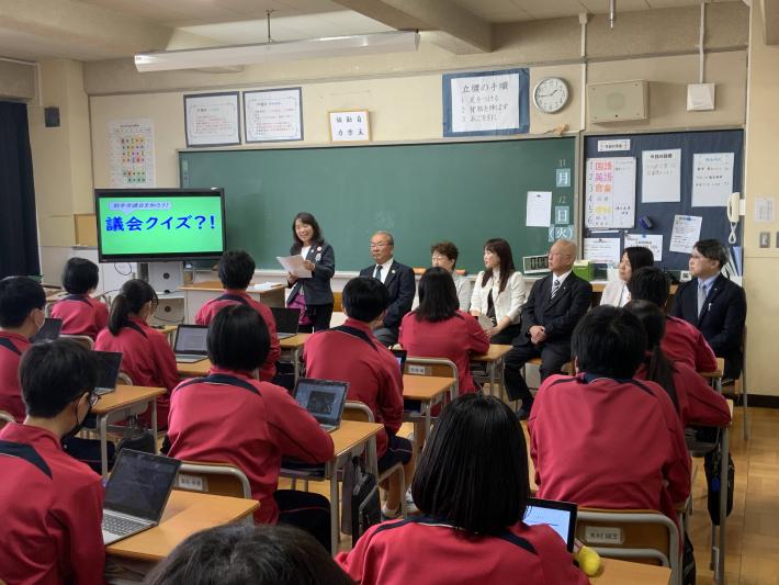 学校の教室で生徒を前に女性のリーダー議員が議会クイズを出している