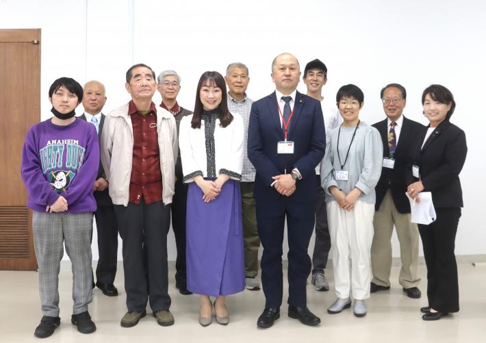 大会議室で男女が横一列に立っている