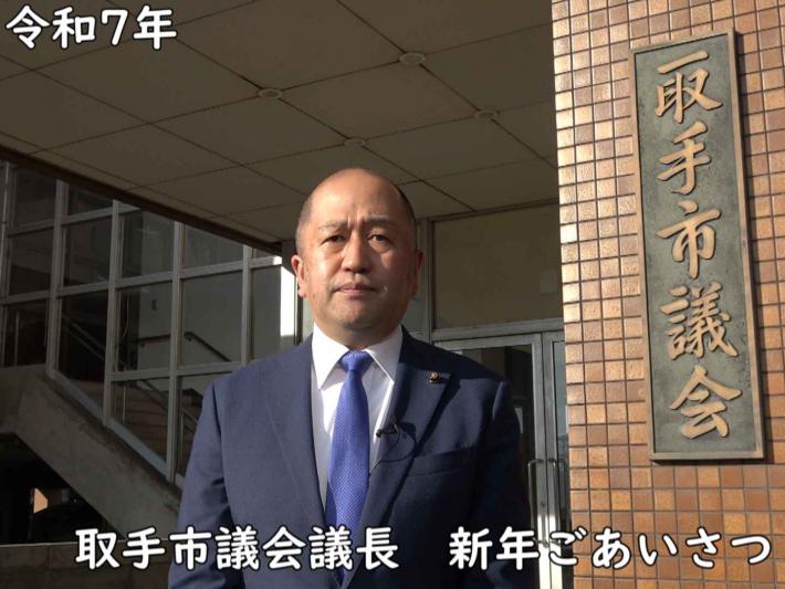 取手市議会の岩澤議長が議会棟の前で令和7年の新年あいさつをしている様子