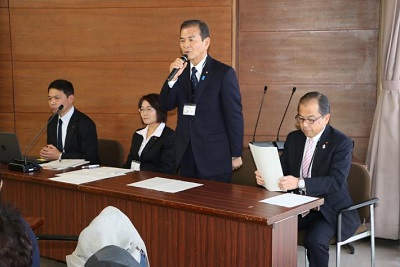 議員4人が並ぶ。右から男性副議長、男性議長、女性副委員長、男性委員長。議長がマイクを持って起立しあいさつする