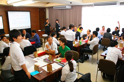 職員と議員が各グループに分かれて座っている。大会議室全体を後方から撮った写真。笑顔があふれる