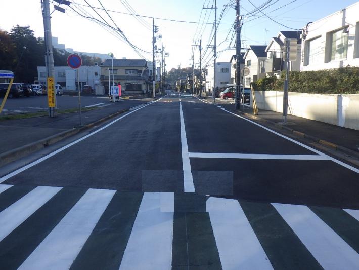 左にコンビニの駐車場、右に建物が見える。横断歩道は白く塗り直されている。