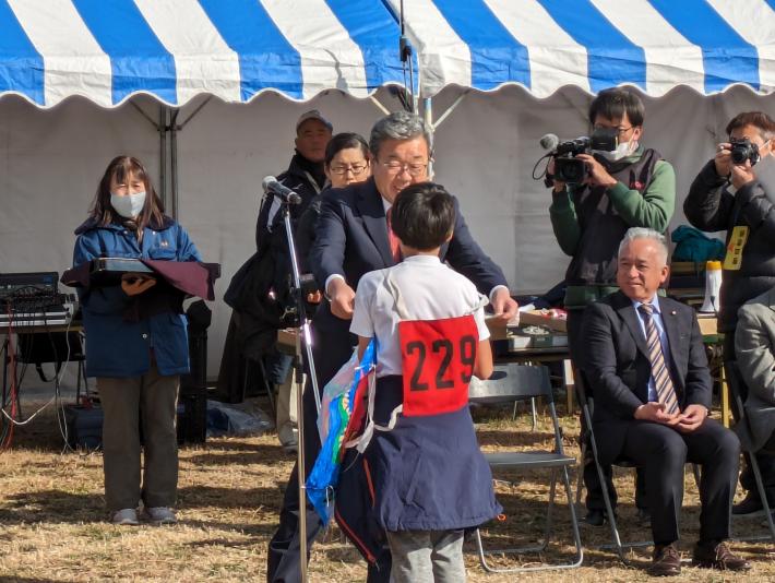 ゼッケンをつけた半袖姿の小学生に賞状を手渡す市長