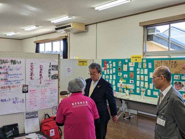 ホールにて展示品を見る市長、教育長と参加者