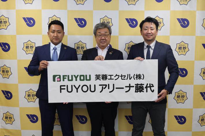 ほどよく絶妙とりでのパネルを背景に「FUYOUアリーナ藤代」の横看板を持ち記念撮影をする男性3人