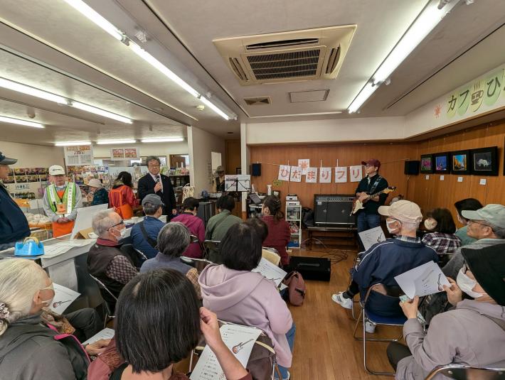 室内でくつろぐ大人たちに向けてあいさつをする男性