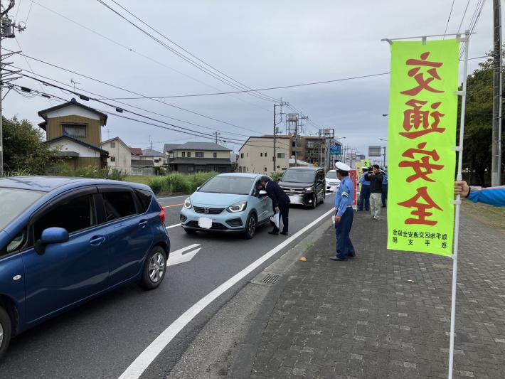 車の窓をのぞいて啓発品を配る男性