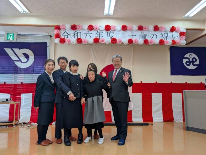 二十歳の祝いと書かれた看板の下に集まる人たち