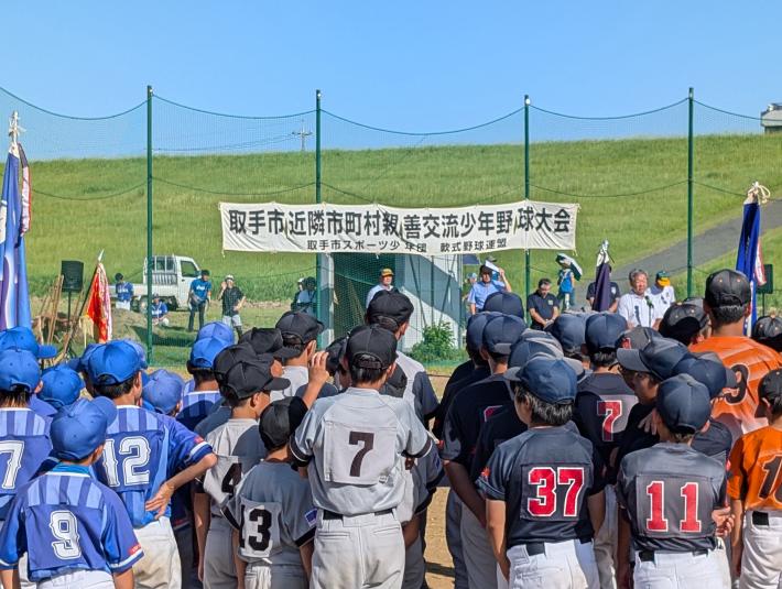 野球のユニフォームを着た子どもたちの前からあいさつをする男性