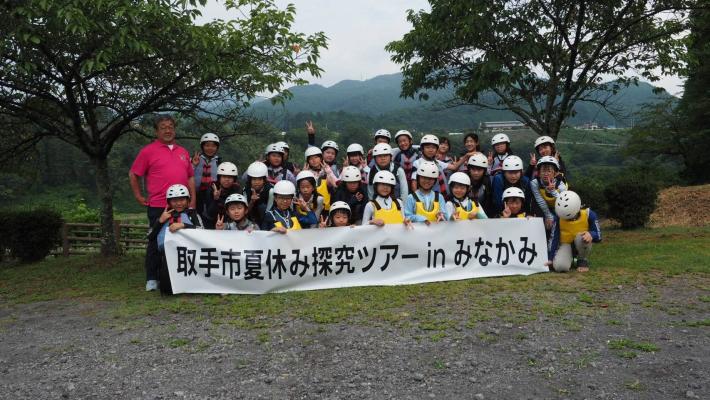 みなかみ町探究ツアーと書かれた横断幕の前で、集合写真に写る小学生と市長