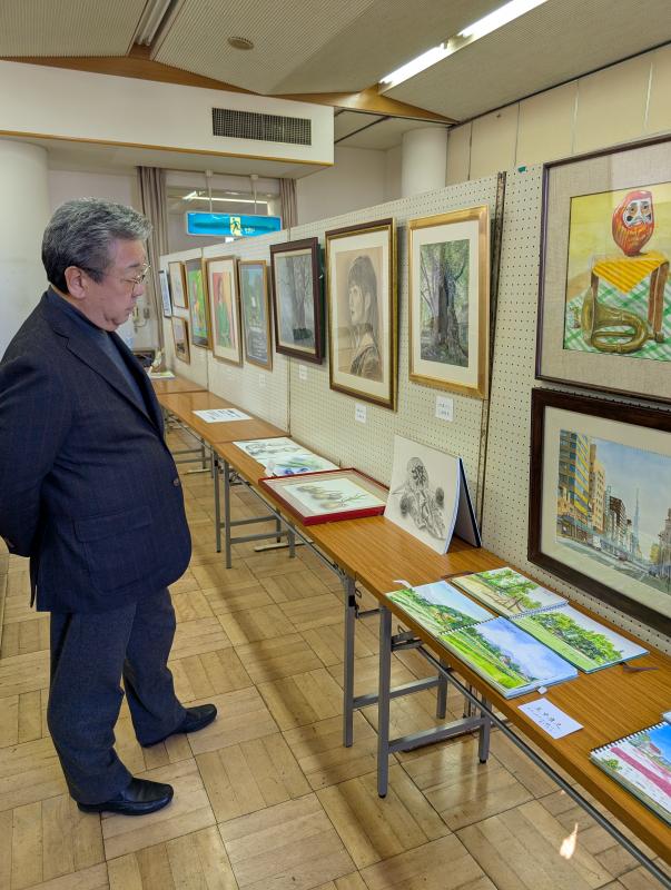 机に並んだ展示物を鑑賞する男性