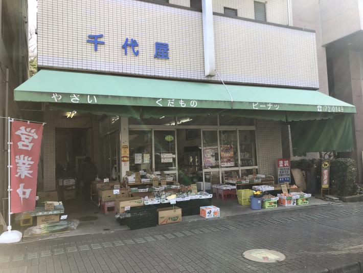 千代屋と書かれた建物に、緑色ののれんがかかっている。店先には、野菜などが並んでいる。