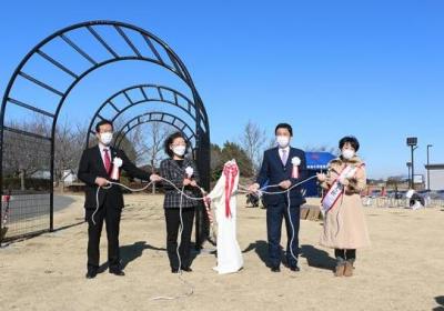 白幕と花のついた柱の横で紐をもって左右に2人ずつ立っている画像