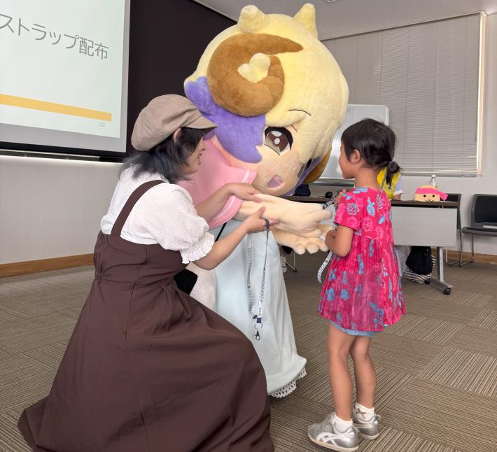 ゆめみんが子どもにオリジナルネックストラップを渡している。