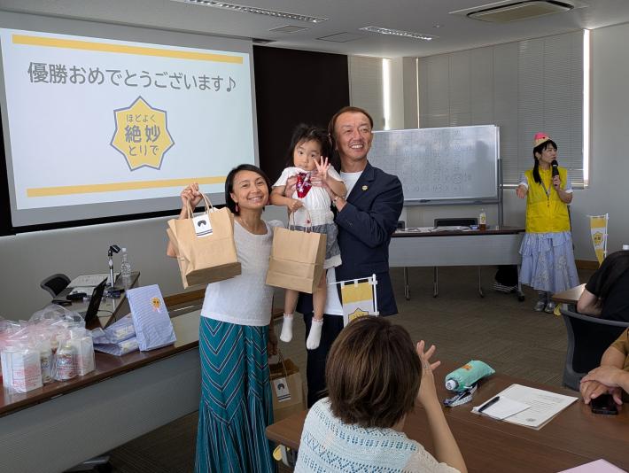 クイズ大会で優勝して景品をもらい、喜んでいる女性と子供と男性