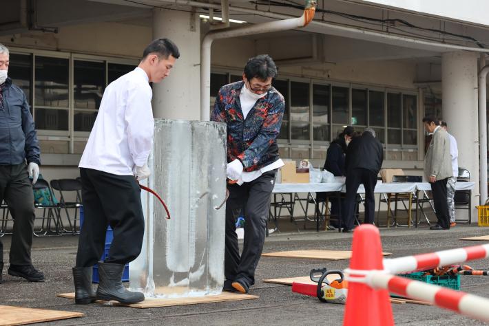 男性2名がやっとこのような道具で氷を運んでいる