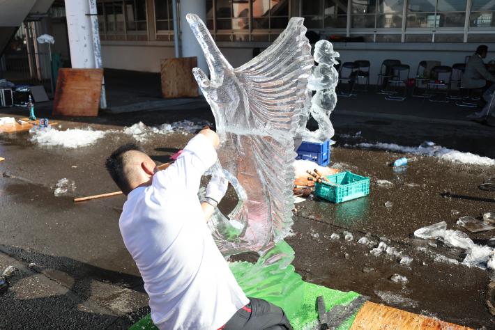 氷のパーツを組み合わせている男性選手