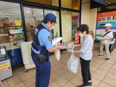 街頭キャンペーンで警察官が女性にチラシを渡している様子