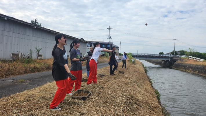 作成した、水質浄化用のEM団子づくりを川に投げている女性