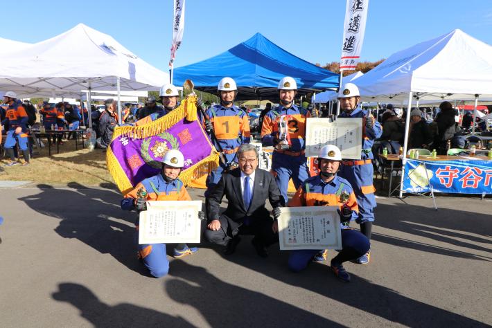 優勝旗、表彰品を手に市長と記念撮影をしている26分団員の様子