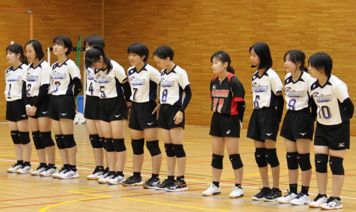 試合開始前に選手11人が整列している様子の写真。